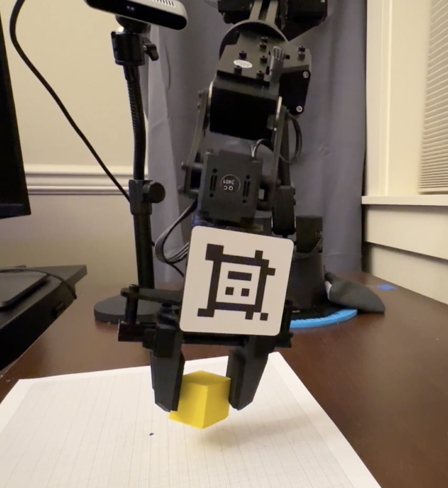 WidowX gripper grasping a block over graph paper